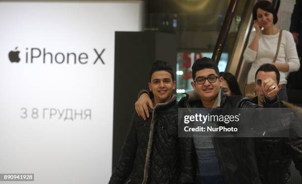 Gesturing men walk out of the Apple promoting table at one of shopping malls in Kyiv, Ukraine, Dec.12, 2017. IPhone X official sales started in...