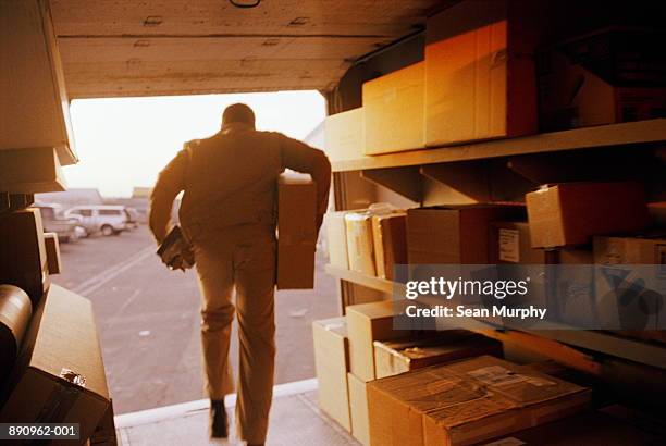 delivery man exiting truck with package, rear view - delivery truck stock pictures, royalty-free photos & images