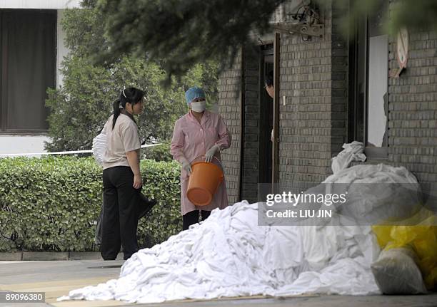 Masked worker talks to others at the Yanxiang Hotel where members of a British student group are quarantined by Chinese authorities over swine flu in...