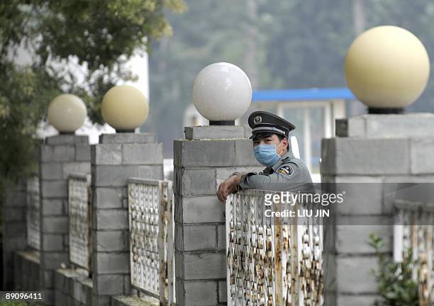 Masked security guard stands by the fence at the Yanxiang Hotel where members of a British student group are quarantined by Chinese authorities over...