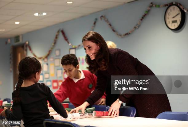 Catherine, Duchess of Cambridge speaks to children, during a visit to the Rugby Portobello Trust's Christmas party which included children affected...