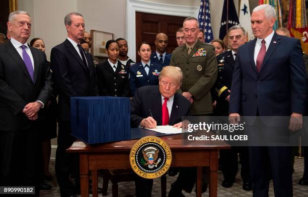 President Donald Trump, surrounded by military officials and members of Congress, including Vice President Mike Pence and Secretary of Defense Jim...