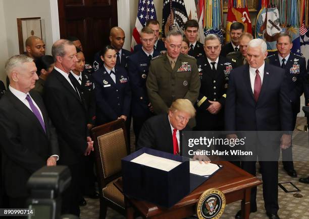 Flanked by members of the military, U.S. President Donald Trump signs the H.R. 2810, National Defense Authorization Act for fiscal year 2018, in the...