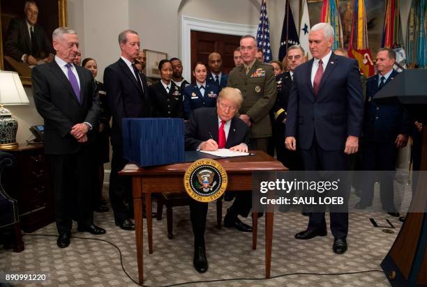 President Donald Trump, surrounded by military officials and members of Congress, including Vice President Mike Pence and Secretary of Defense Jim...