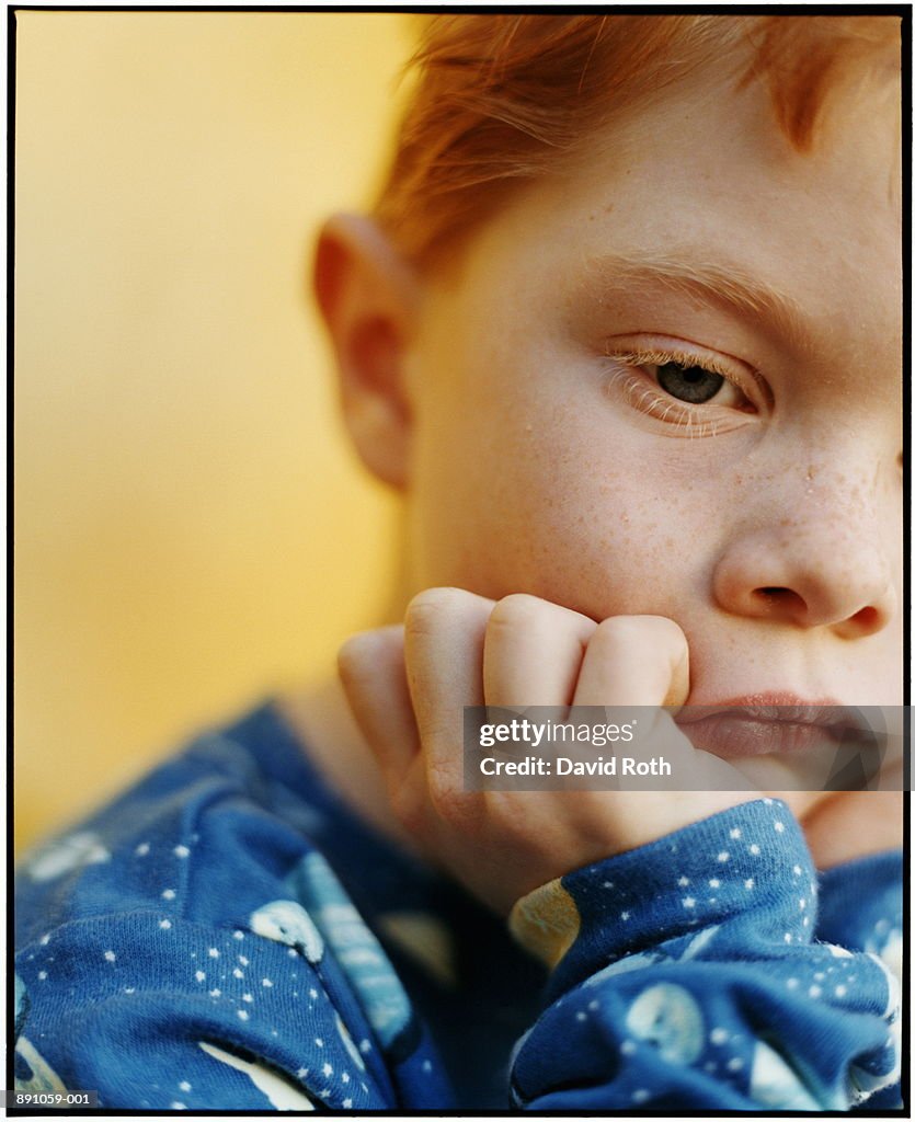 Boy (4-6) looking pensive, chin resting on hand