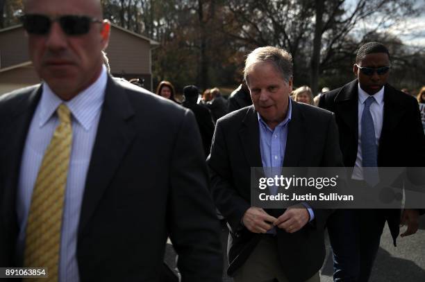 Democratic senatorial candidate Doug Jones walks with his security detail after greeting voters outside of a polling station at Sixth Avenue Baptist...