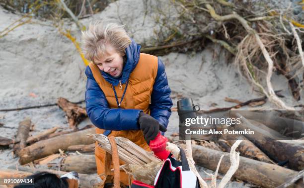 la mujer madura atractiva activa 50 años bebiendo el té caliente del termo en la playa de invierno el frío mar del báltico - 50 54 years fotografías e imágenes de stock