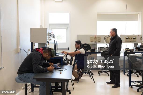 Teacher oversees students learning how to fix the electronic systems of an aircraft at the University of Aeronautics in Queretaro in the town of...