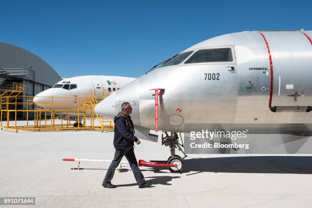 Teacher passes in front of a Bombardier Inc. CJ300 aircraft at the University of Aeronautics in Queretaro in the town of Colon, Queretaro state,...