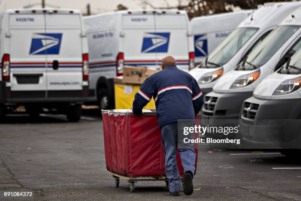 Letter carrier pushes a package bin towards a delivery vehicle at the United States Postal Service Joseph Curseen Jr. And Thomas Morris Jr....