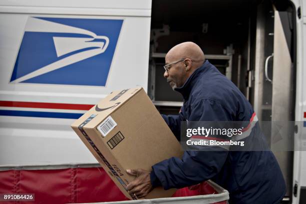 Letter carrier lifts an Amazon.com Inc. Package from a bin while preparing a vehicle for deliveries at the United States Postal Service Joseph...