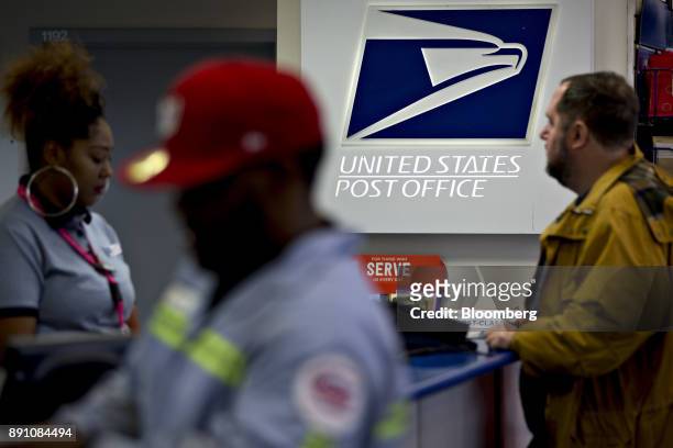 Signage is seen past customers and a postal clerk, left, at the United States Postal Service Joseph Curseen Jr. And Thomas Morris Jr. Post office...