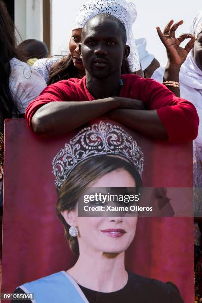 Man poses with a Queen Letizia of Spain's portrait as he waits to see her prior to an official lunch with Senegalese First Lady Marieme Faye Sall on...