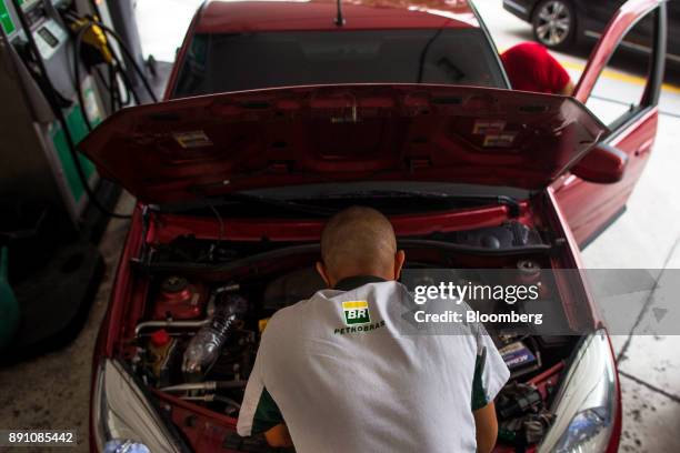 An attendant looks under the hood of a vehicle at a Petrobras Distribuidora SA gas station in Sao Paulo, Brazil, on Monday, Dec. 11, 2017. Petroleo...