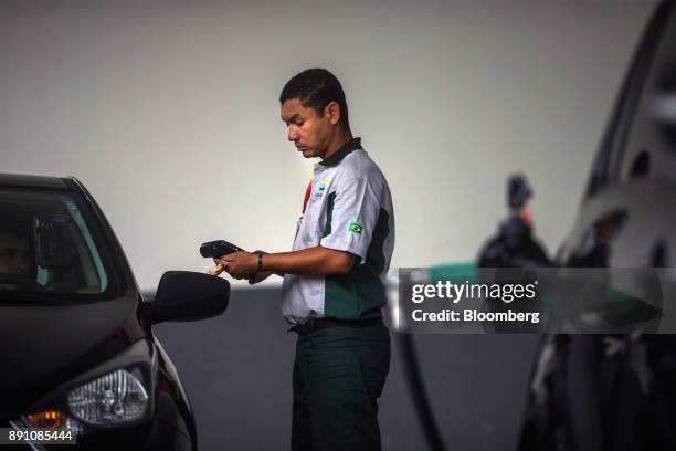 An attendant uses a credit card reader to charge a customer for fuel at a Petrobras Distribuidora SA gas station in Sao Paulo, Brazil, on Monday,...