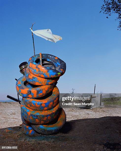 paint ball battle, man hiding behind tires, holding white flag - surrender flag stock pictures, royalty-free photos & images