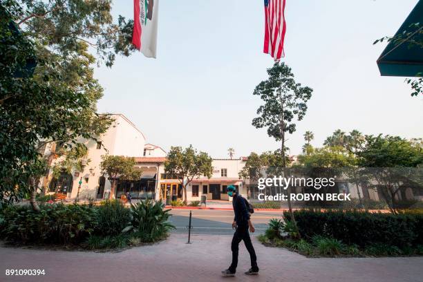 Man walks wearing a face mask to protect himself from smoke and ask from the Thomas Fire walks on State Street, the main shopping street in Santa...