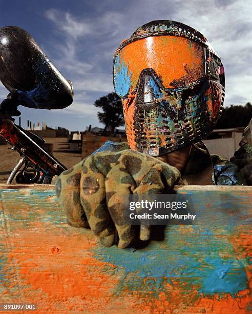 paint ball player in camouflage wearing helmet covered in paint - paintball stock pictures, royalty-free photos & images