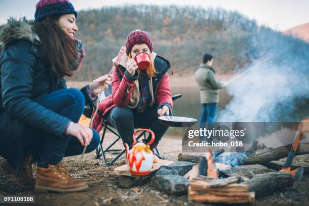 campers next to the campfire preparing food - camping campfire stock pictures, royalty-free photos & images