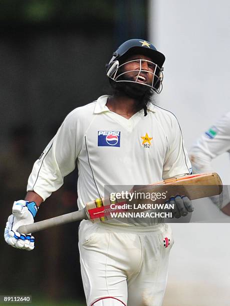Pakistan cricketer Mohammad Yousuf walks back to the pavilion following his dismissal as Sri Lankan cricketers look on during the first day of the...