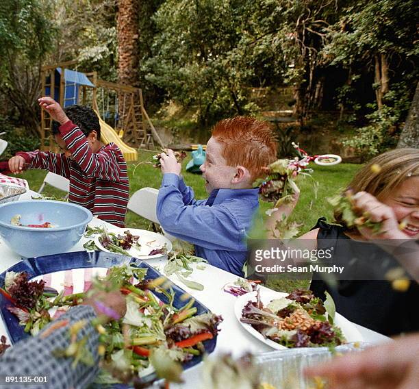 children (5-7) in backyard throwing food at each other - food fight stock pictures, royalty-free photos & images