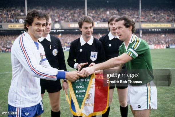 Michel Platini , the captain of France, exchanges pennants with the Republic of Ireland captain Liam Brady watched by the match officials prior to...