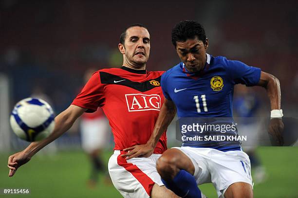 Footballer John O'Shea of Manchester United fights for the ball with Malaysian player Mohammad Azmi Muslin during a friendly match at the National...
