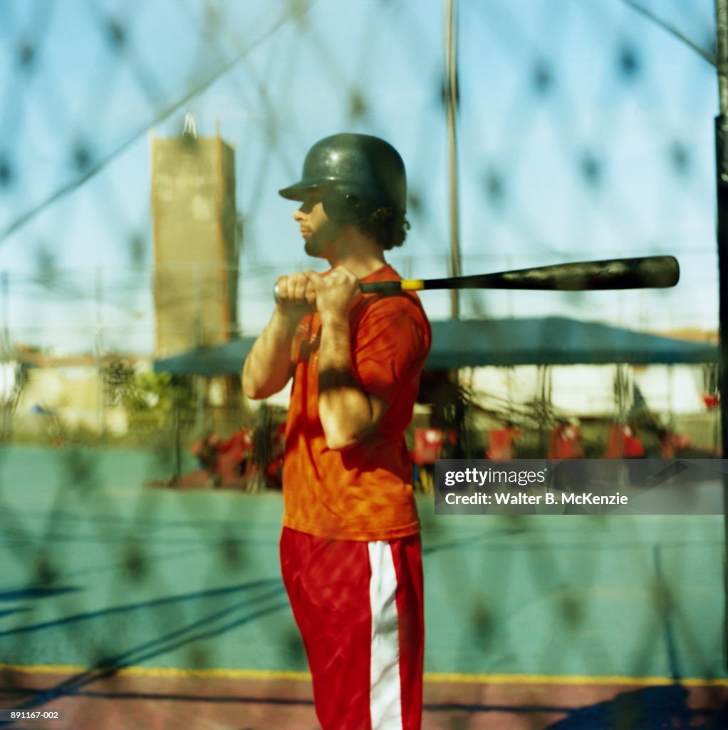 Man with bat in batting cage