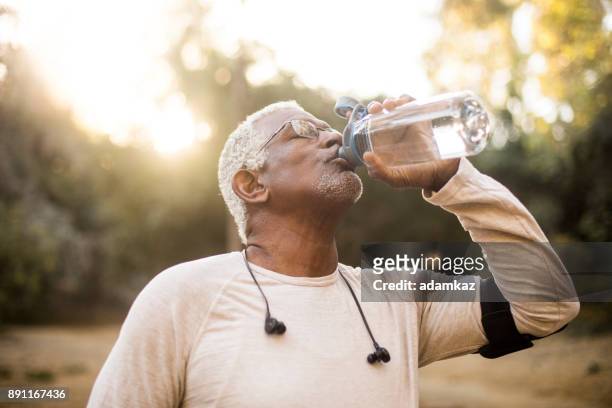 eau potable afro-américain senior - fitness armband photos et images de collection