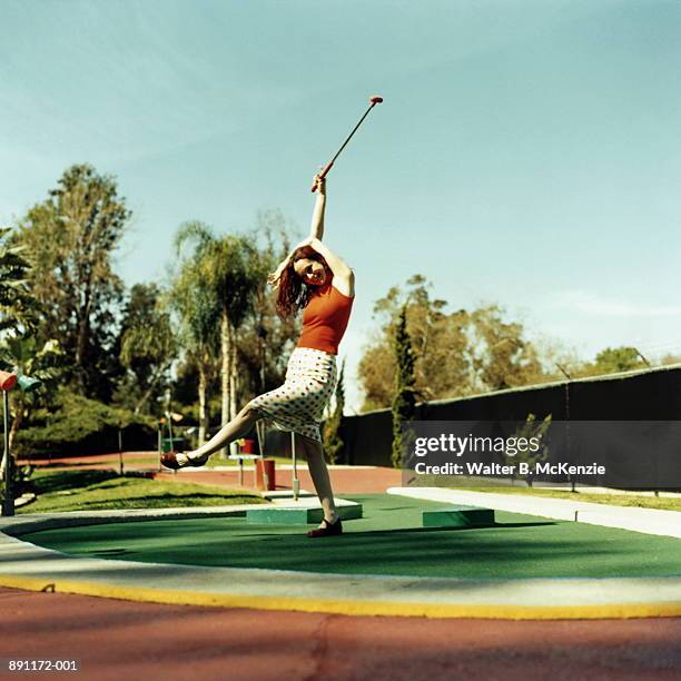 woman expressing joy on putting green at miniature golf course - minigolf foto e immagini stock