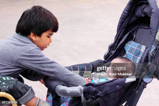 elder brother taking care of his little brother - cute pakistani boys fotografías e imágenes de stock