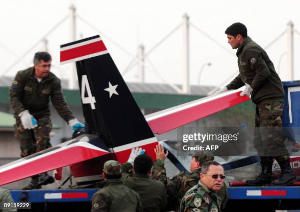 Officers of the Chilean Air Force carry the wreckage of an airplane that fall in Santiago's Fish Market during a training flight, onto a truck on...