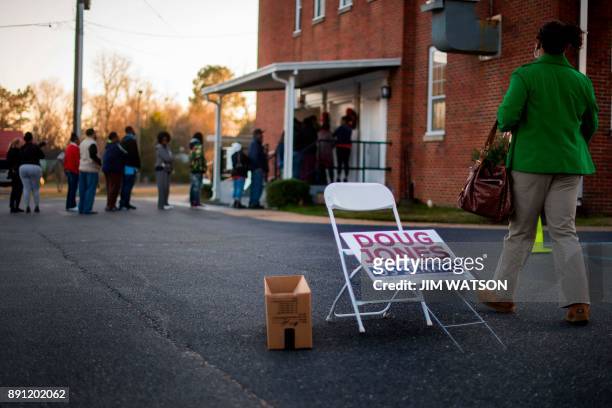Woman passes a placard for Democratic Senatorial candidate Doug Jones as she walks over to get in the long line to vote at Beulah Baptist Church...