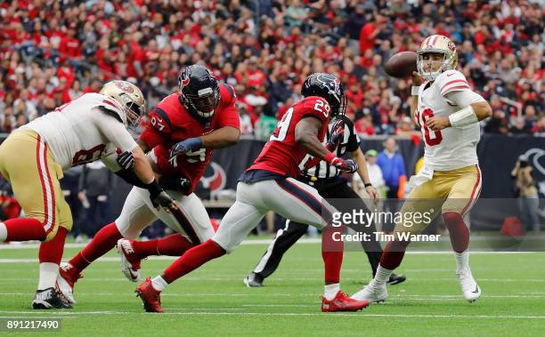 Jimmy Garoppolo of the San Francisco 49ers looks to pass under pressure by Andre Hal of the Houston Texans and Angelo Blackson in the second half at...