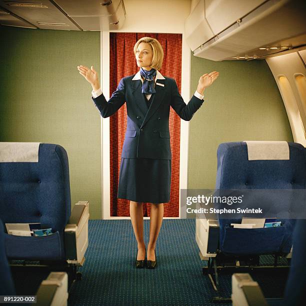 flight attendant showing where emergency exits are on plane - tripulación fotografías e imágenes de stock