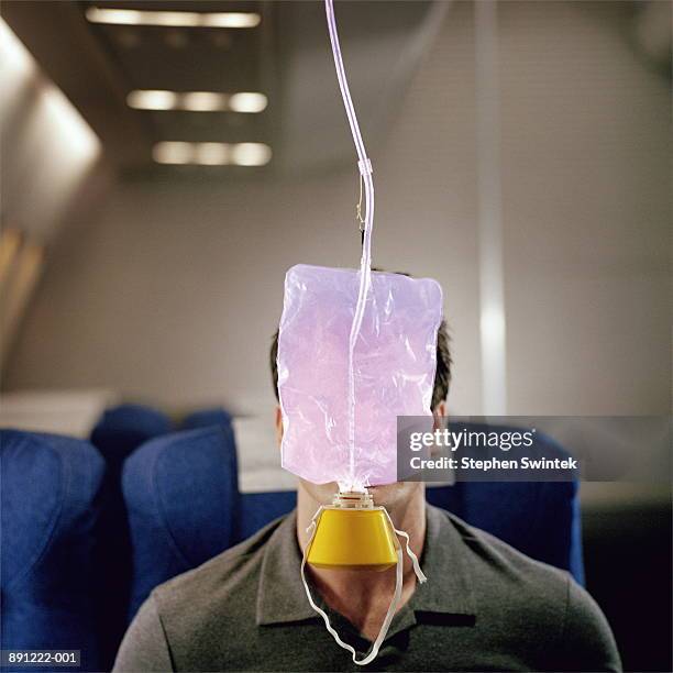 man with oxygen mask hanging in front of face, on airliner - sauerstoffmaske stock-fotos und bilder