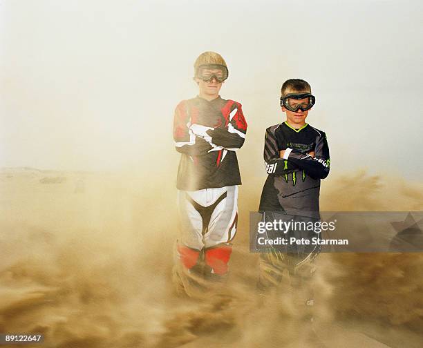 two boys being blasted with sand by motorcycle. - safety glasses stock pictures, royalty-free photos & images