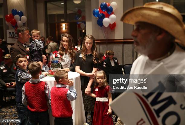 Mike Tate holds his son, Seth Tate, as he and his family await the arrival of Republican Senatorial candidate Roy Moore for his election night party...