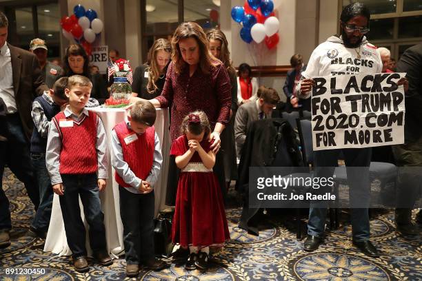 Supporters bow their heads in prayer as they await the arrival of Republican Senatorial candidate Roy Moore for his election night party in the RSA...
