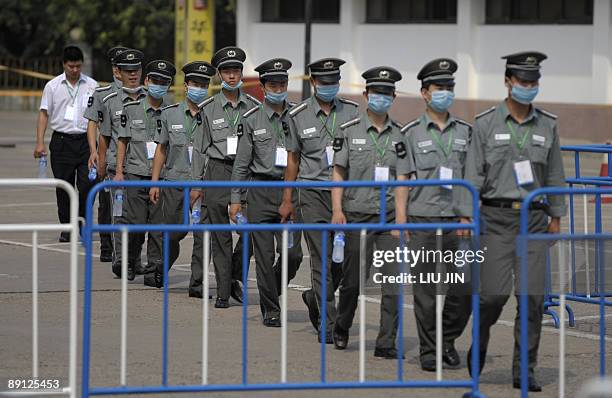 Group of masked Chinese security guards walk outside the Yan Xiang Hotel in Beijing on July 21 where a group of foreigners are being quarantined over...