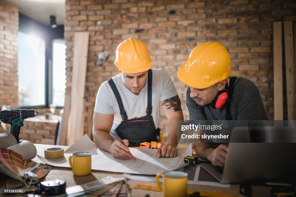 Werknemers in de bouw samen te werken bij het analyseren van de woningbouw project in appartement.