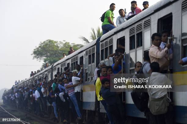 Sri Lankan passengers hold on to door handles as they travel on overfilled train carriages during a nationwide railway strike in Colombo on December...