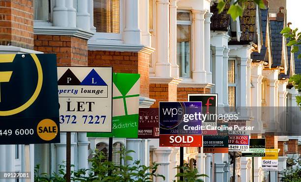 row of houses with for sale signs in front of them - immobilienbüro stock-fotos und bilder