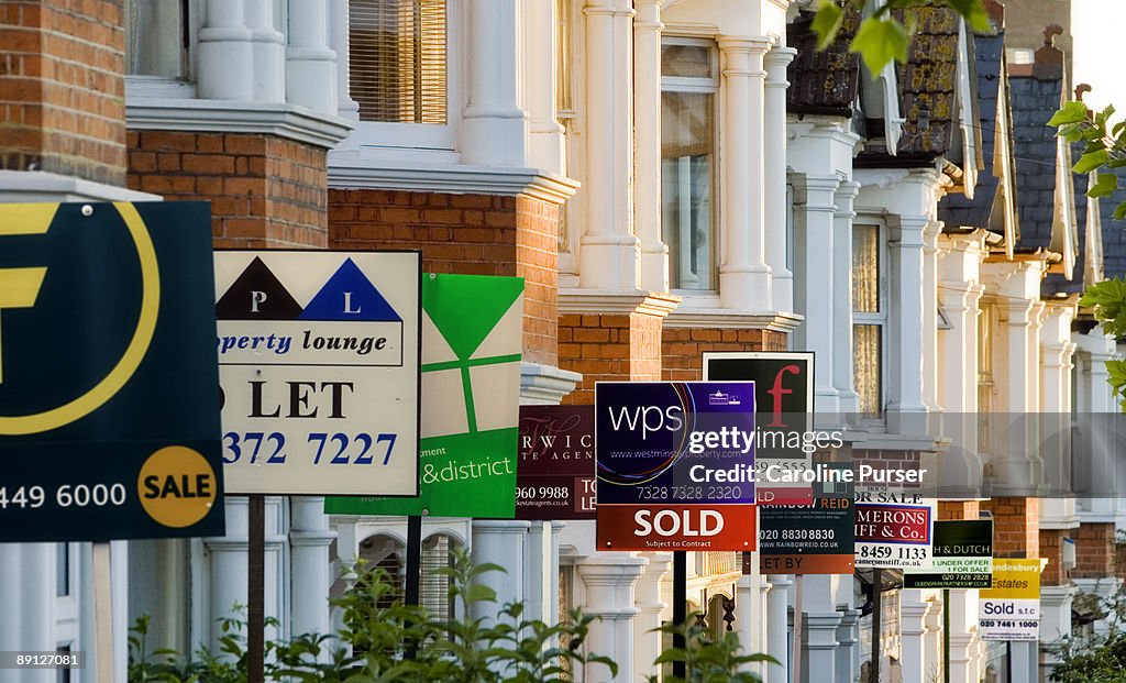 Row of houses with for sale signs in front of them