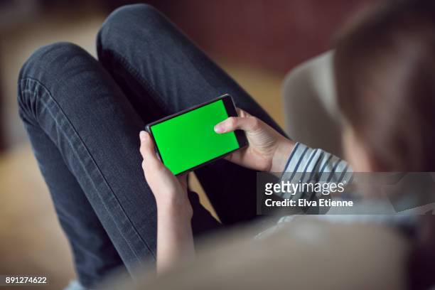 teenager using a mobile phone with a green screen - horizontal stock-fotos und bilder