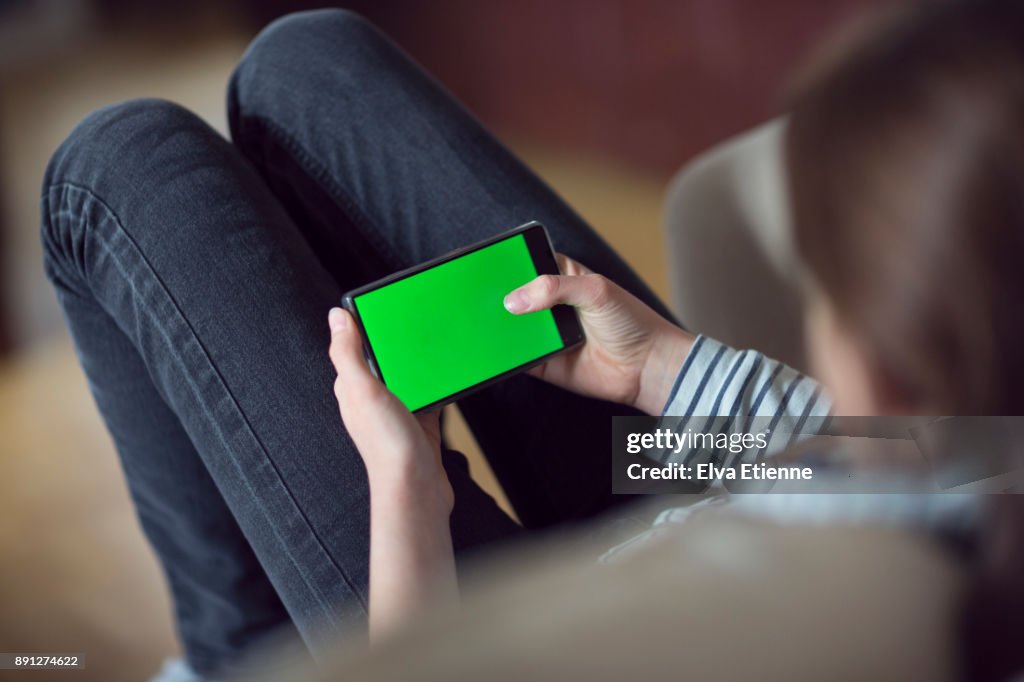 Teenager using a mobile phone with a green screen