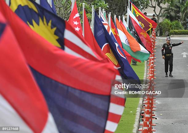 Thai soldier gestures from his position securing a road lined with the flags of member countries of Association of Southeast Asian Nations and...