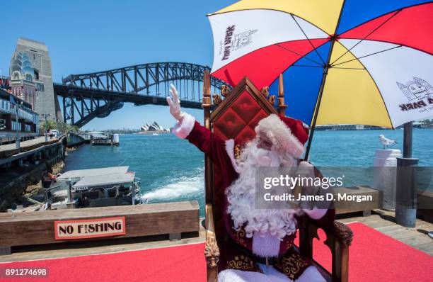 Santa Claus uses a umbrella to keep cool in the hot summer sunshine at Luna Park on December 13, 2017 in Sydney, Australia. Luna Park has pulled some...