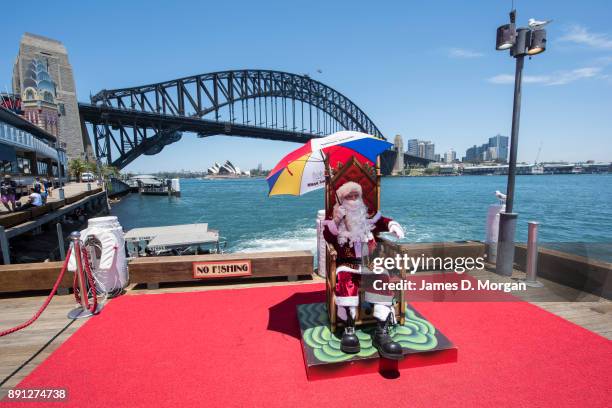 Santa Claus uses a umbrella to keep cool in the hot summer sunshine at Luna Park on December 13, 2017 in Sydney, Australia. Luna Park has pulled some...