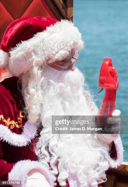 Santa Claus uses a water spray fan to keep cool in the hot summer sunshine at Luna Park on December 13, 2017 in Sydney, Australia. Luna Park has...